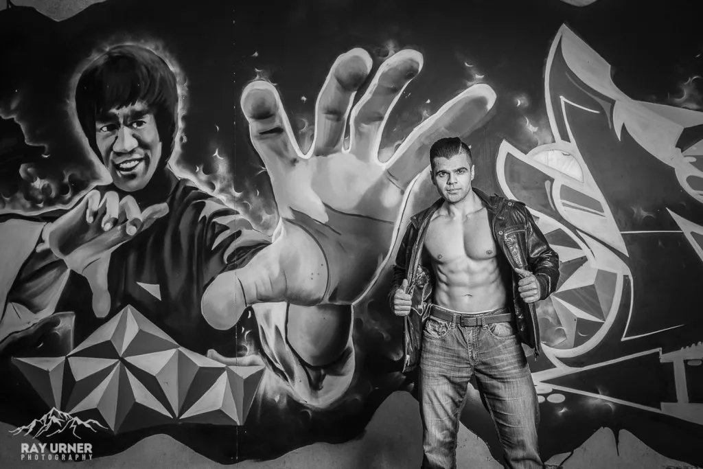 Gurv Sihra from the Bollywood Boyz posing against a Bruce Lee mural